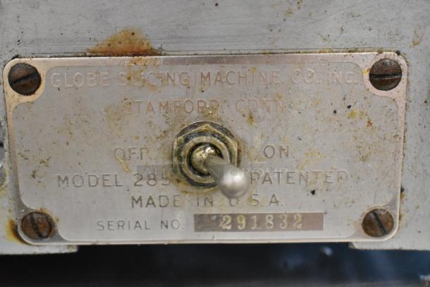 Globe 285 metal commercial meat slicer with blade sharpener, visible model and serial number plate, 115V, 1 phase.
