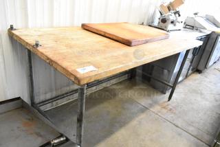 Butcher block wooden table with metal legs, worn surface, includes rectangular board, ID tag visible, sturdy construction.