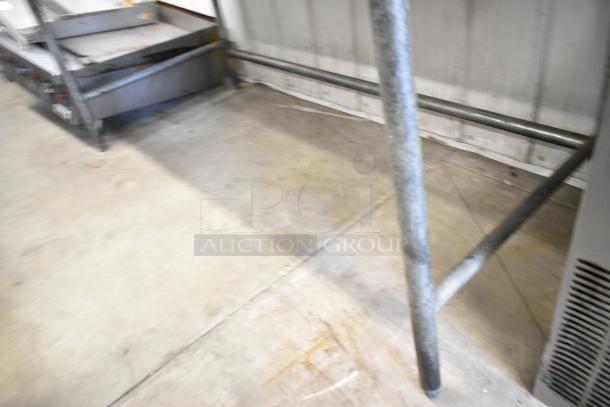 Butcher block wooden table with sturdy metal legs, showing industrial style. Appears in good condition, no visible markings.
