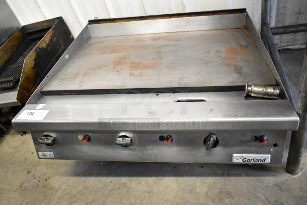 Garland stainless steel commercial countertop gas griddle, slightly worn, visible brand logo, adjustable knobs.