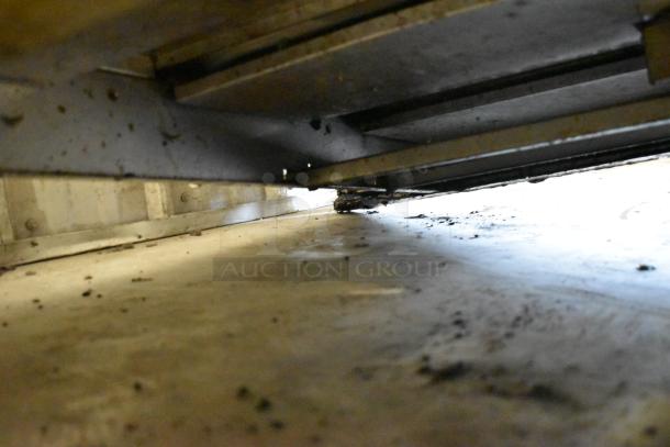 Garland Stainless Steel Commercial Flat Top Griddle, gas-powered, underside view showing metal frame and wear.