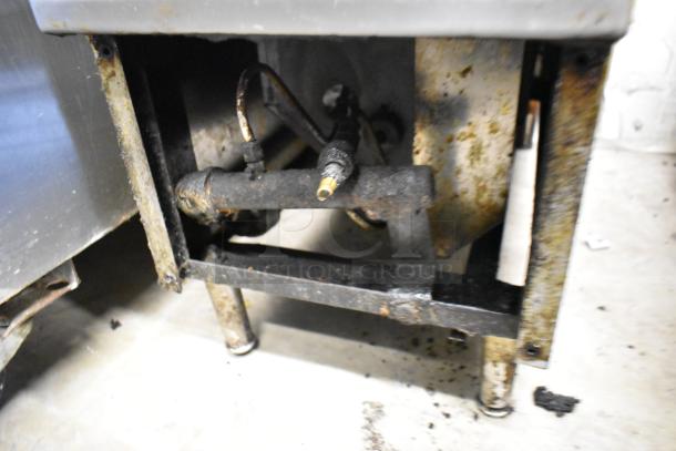 Metal commercial gas charbroiler grill with visible rust and wear. Displaying underside components and gas connections. Used condition.