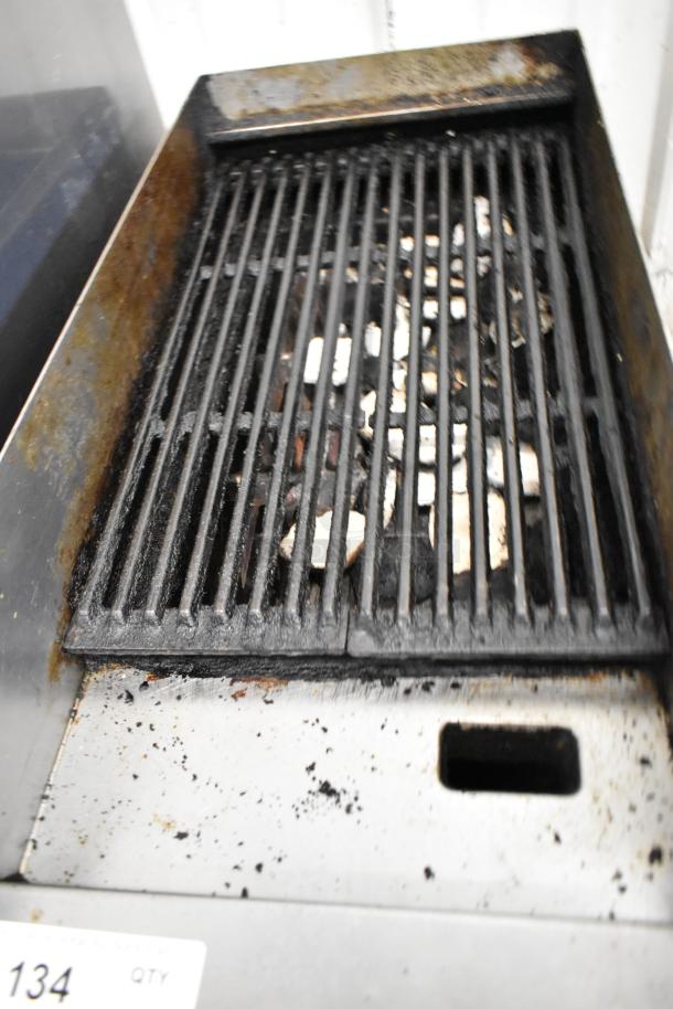 Metal commercial gas-powered charbroiler grill, used condition, visible grease stains and char marks on grates.