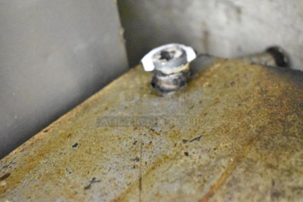 Close-up of a metal surface with visible wear and a screw, part of a commercial gas-powered charbroiler grill.