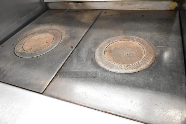 Jade Range stainless steel commercial gas 2-burner range with oven, over shelf, backsplash, and commercial casters, showing burner surface.