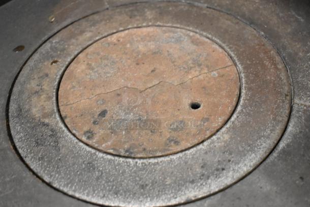 Close-up of a well-used burner from a Jade Range commercial gas stove, showing wear and surface cracks.