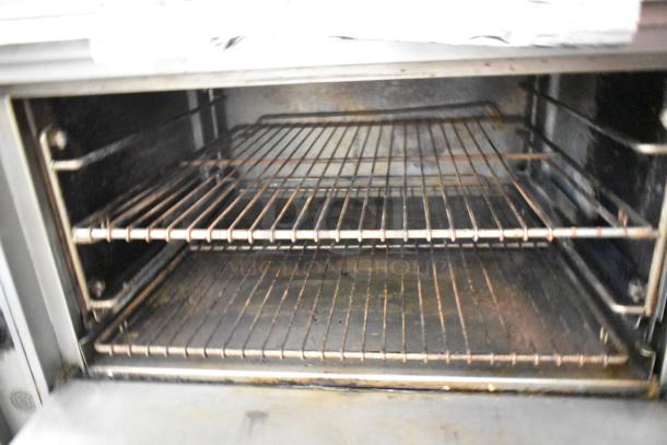 Jade Range stainless steel commercial gas 2-burner range with oven, overshelf, backsplash, on casters. Interior of oven shown.