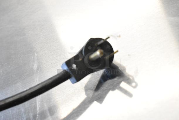Close-up of a power cord plug against a stainless steel surface, related to the Beverage Air UCF27A-23 freezer.
