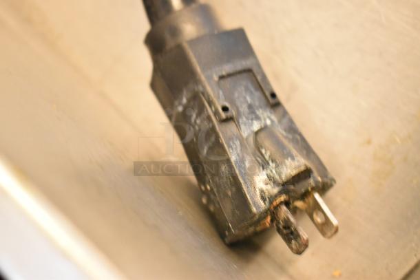 Close-up of a worn power plug from a commercial electric griddle, showing visible wear on the prongs and casing.
