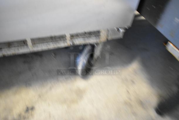 Stainless steel Beverage Air UCR34HC 2-door undercounter cooler on commercial casters, 115V, 1 phase. Blurry image of wheel and base.