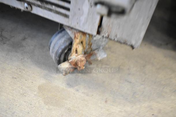 A rusty caster on a Beverage Air stainless steel commercial undercounter cooler. Visible wear, on a concrete floor.