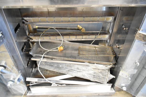Rotisol 1160.4 metal commercial natural gas-powered rotisserie oven in used condition. Includes racks and interior components.