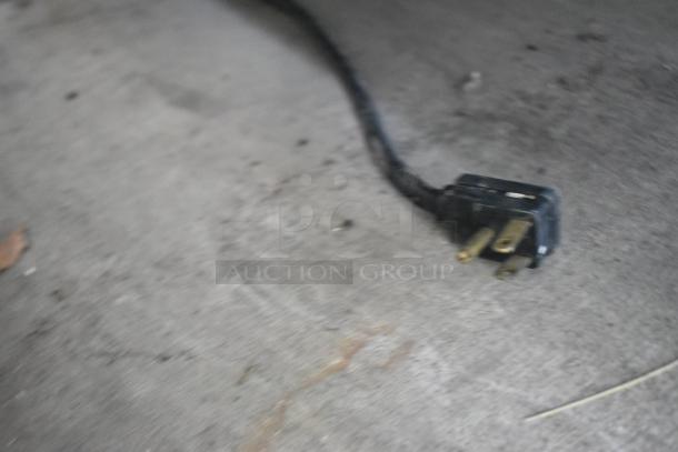 Blurry close-up image of an electrical plug, not clearly showing the Traulsen G10010 cooler features.