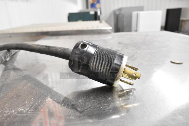 Power plug for Hoshizaki KML-631MAH ice maker, black and gold connectors, resting on stainless steel surface.