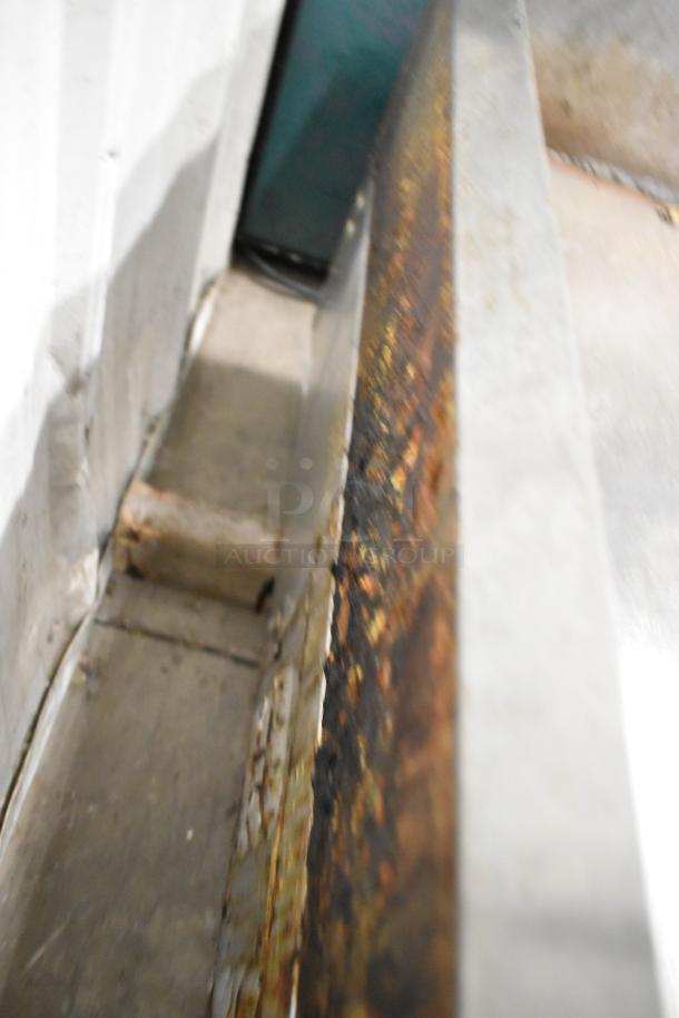 Lang stainless steel commercial countertop flat top griddle, side view, visible wear and rust, model unspecified.