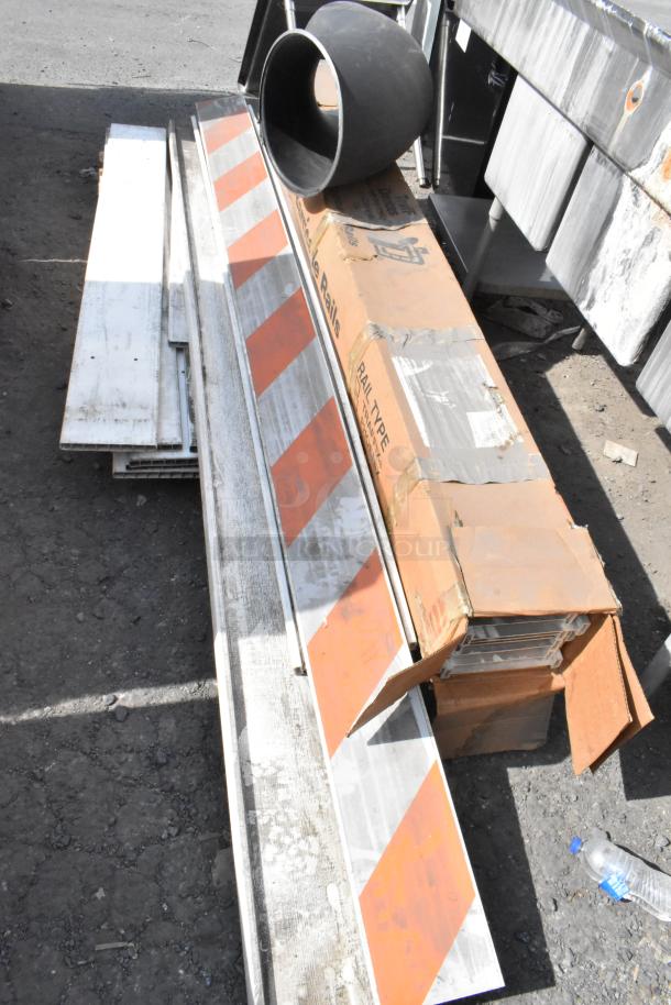 Pallet lot containing various items including barricade rails, metal pipes, and cardboard boxes, showing wear.