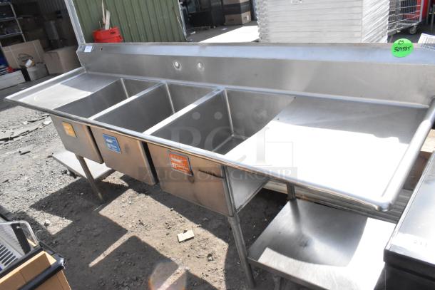 Stainless Steel 3 bay sink with dual drain boards, features labeled wash, rinse, and sanitize sections, in used condition.