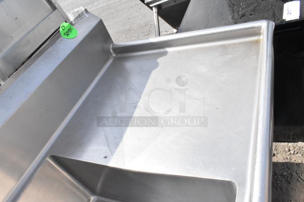 Stainless Steel 3 bay sink with dual drain boards, visible green label, smooth surface, slight wear, ideal for commercial use.