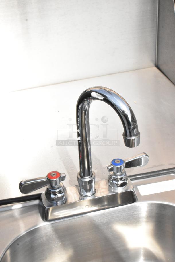 QualServ stainless steel portable sink with dual faucet handles, mounted on commercial casters, ideal for businesses.