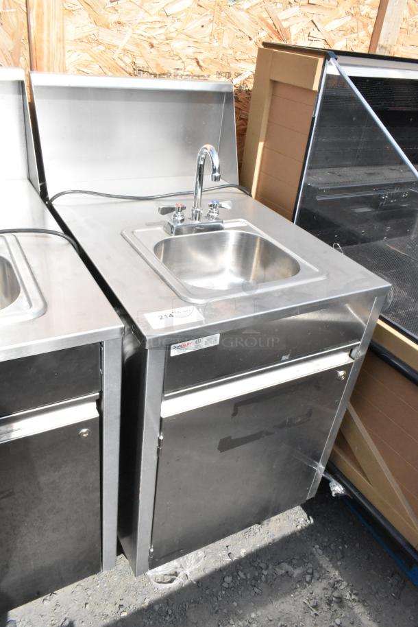 QualServ stainless steel portable sink with faucet, commercial casters, and storage. Used condition. Labels on front panel.