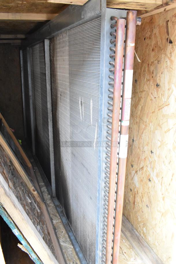 Brand new evaporator coil in crate, featuring metal fins and copper piping; pristine condition.