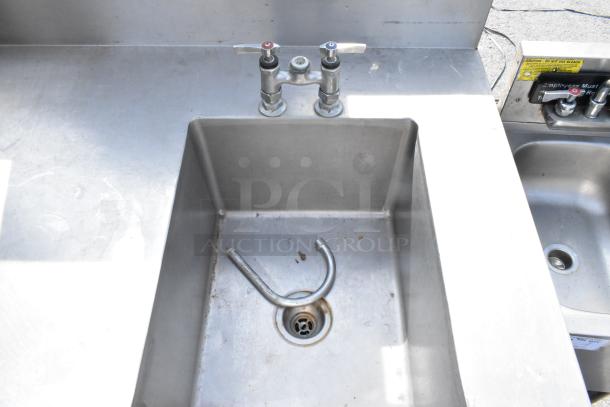 Stainless steel single bay sink with gooseneck faucet and under shelf, used condition, minor surface marks, attached plumbing fixtures.