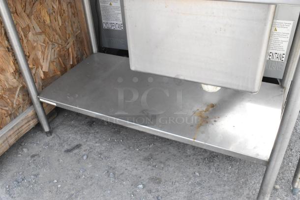 Stainless steel single bay sink with under shelf, visible wear, sturdy metal frame, signs label "Cyclopentane" visible.