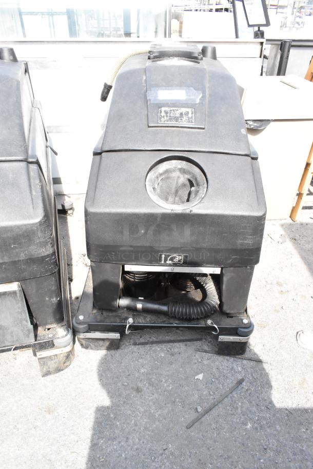 NSS Wrangler 2625 DB Floor Scrubber, industrial-grade, black, visible wear, includes hose and markings for operation use.