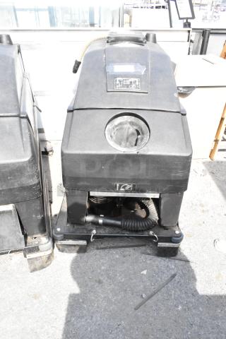 NSS Wrangler 2625 DB Floor Scrubber, industrial-grade, black, visible wear, includes hose and markings for operation use.