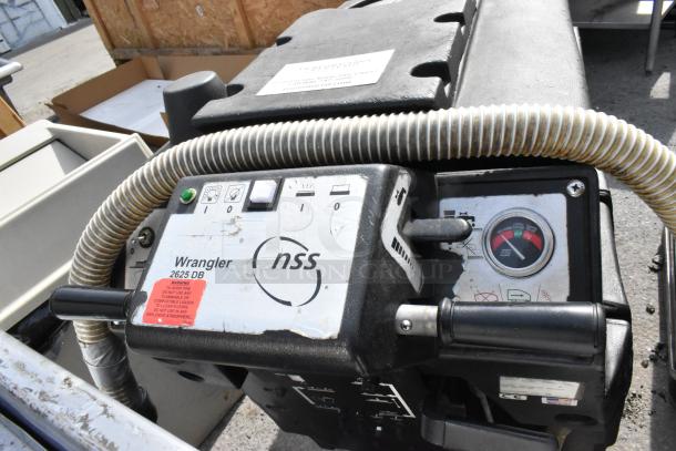 NSS Wrangler 2625 DB floor scrubber, visible controls and gauges, used condition with warning label.