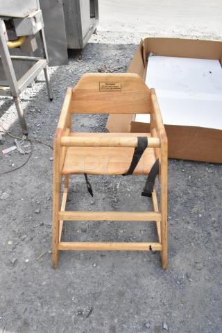 Wooden high chair with natural finish, visible safety label, and black straps. Solid condition, used outdoors. Set of three.