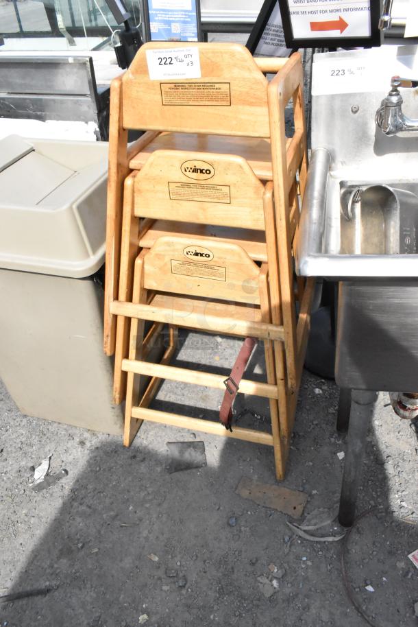 Three wooden high chairs with Winco branding, stacked. Includes safety straps. Used, showing some signs of wear.