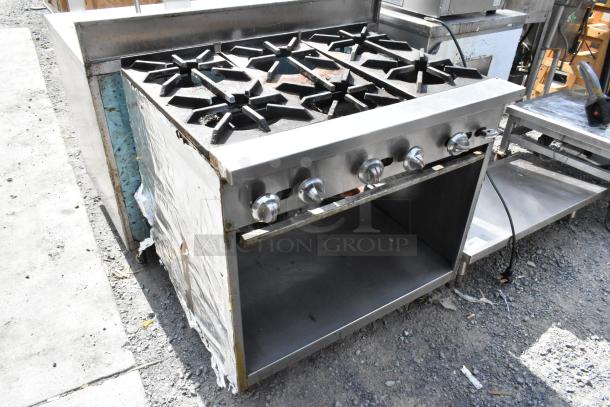 Stainless steel commercial 6 burner gas range with under shelf, showing signs of use, ideal for professional kitchens.