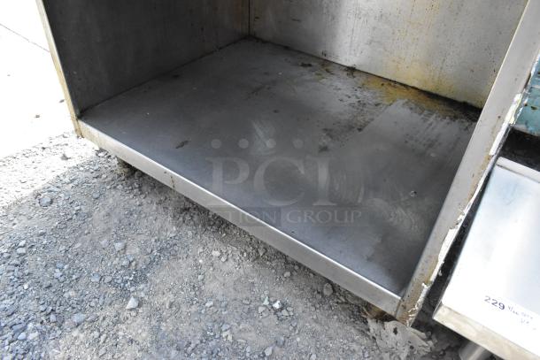 Stainless steel commercial gas range with 6 burners, under shelf, some surface marks and wear visible.