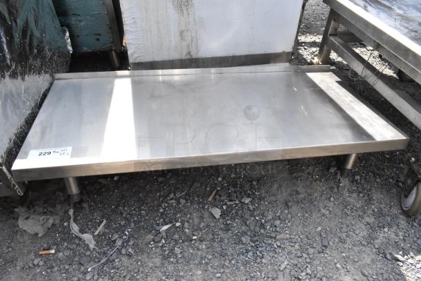 Stainless steel equipment stand with shelf, industrial use, sturdy condition, labeled “229.” Grime present on surface.