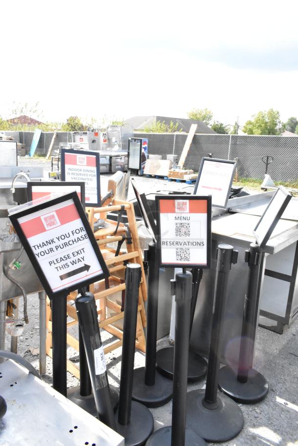 9 black stanchions with signage frames, featuring labels for dining directions. Good condition, suitable for crowd control.