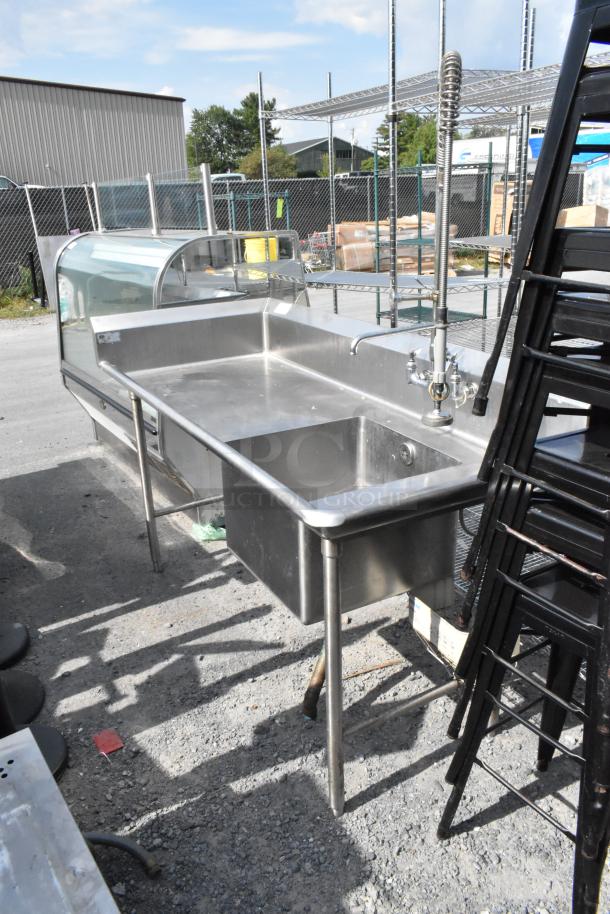 Stainless steel single bay sink with faucet and spray nozzle attachment, durable, suitable for commercial use.
