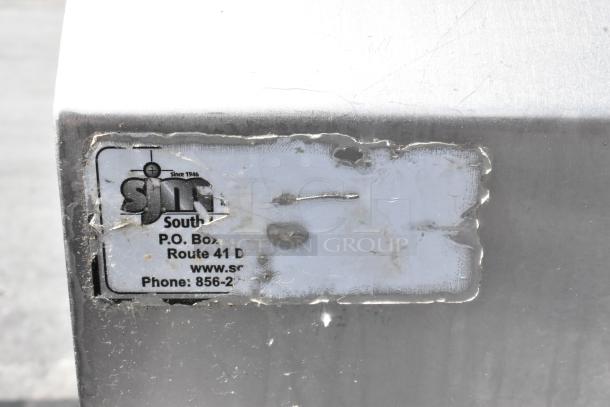 Stainless steel single bay sink with faucet and spray nozzle, featuring a visible label with company contact information.