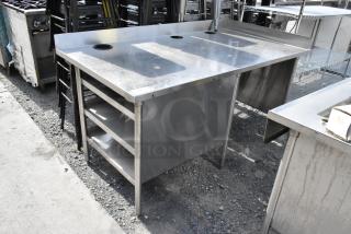 Stainless steel table with three under shelves, side splash guards, and circular cutouts on top. Industrial-grade and durable.
