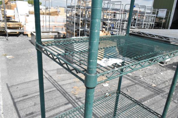 Four-tier green wire shelving unit in good condition with auction tag. Buyer must dismantle and arrange freight.