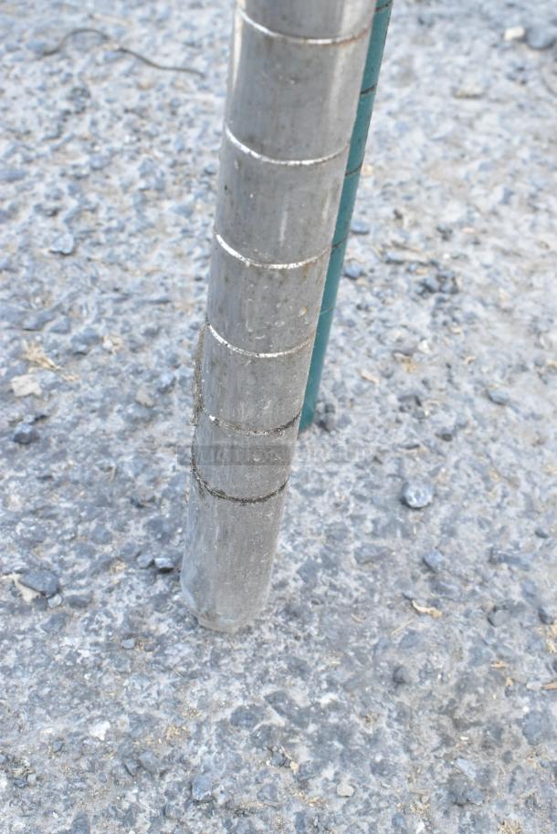 Chrome finish 4-tier wire shelving unit leg detail on gravel. Buyer must dismantle. Consider freight for shipping.