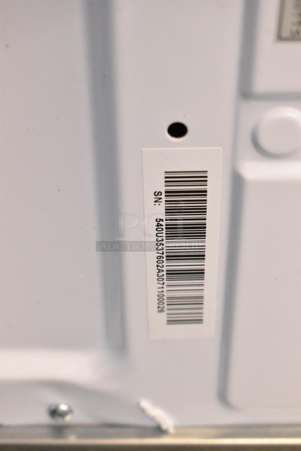 Barcode and serial number label on the back of a KoolMore KM-MOT-1SS stainless steel microwave, indicating model and details.