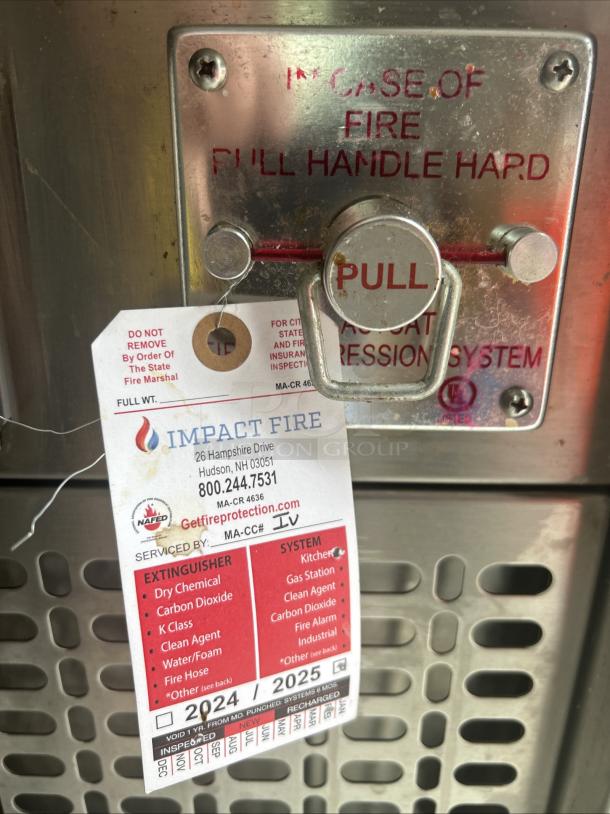 "Fire suppression system handle on Evo 48E-10-0148-EVT griddle. Impact Fire tag shows service info and extinguisher details."