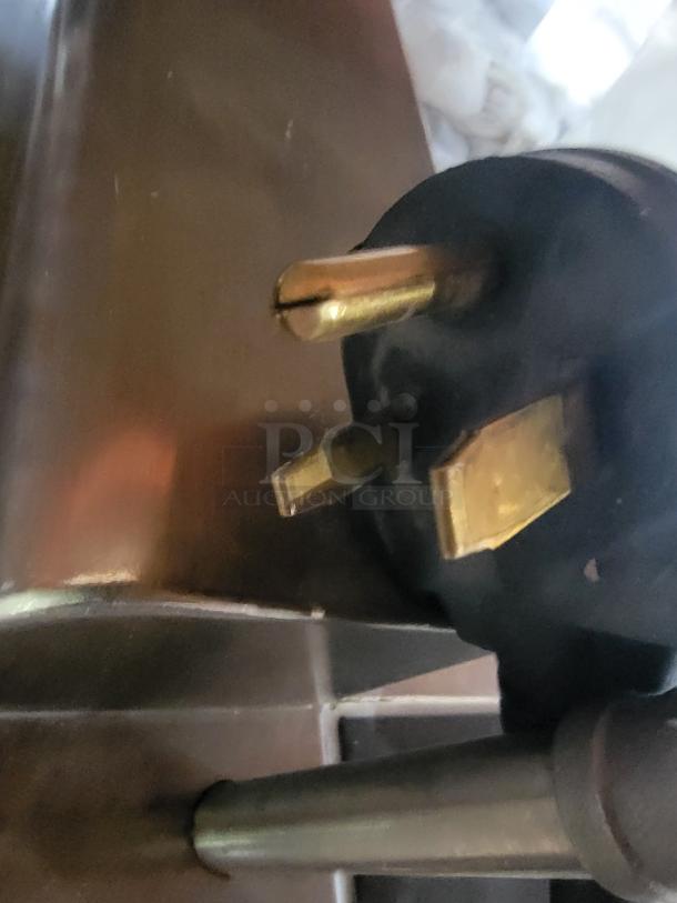 Close-up of the plug of an Evo 48E-10-0148-EVT ventless electric griddle. Gold prongs, sturdy black casing.
