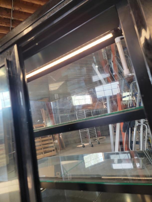 Structural Concepts NE3627RSV refrigerated display case with glass shelves, black frame, and interior lighting. Tested and working.