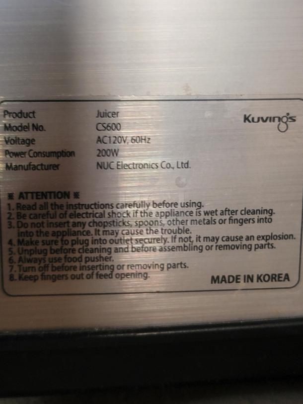 Kuvings CS600 juicer label showing model, voltage (AC120V, 60Hz), power (200W), and manufacturing details. Made in Korea.
