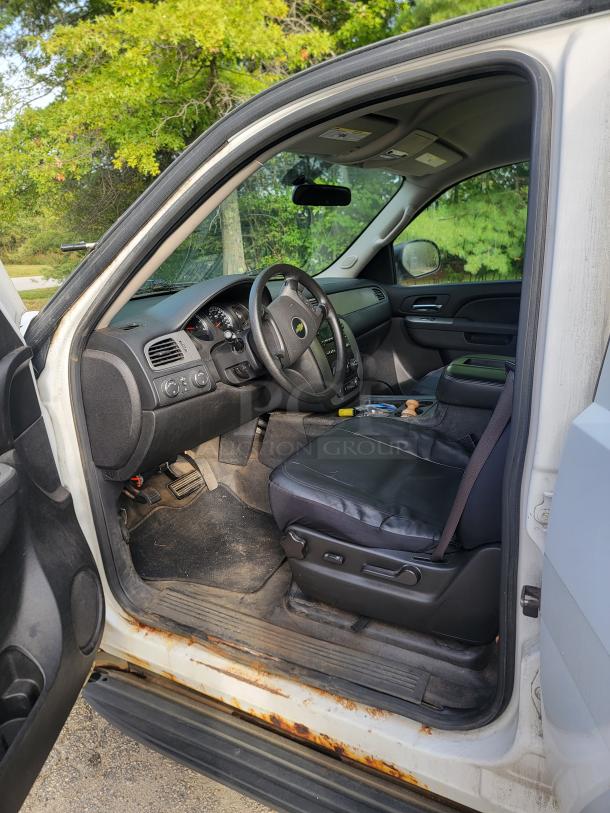 Interior of a white 2012 Chevrolet Tahoe 4x4, showing a well-maintained driver's seat and dashboard, displaying rust on door frame edge.