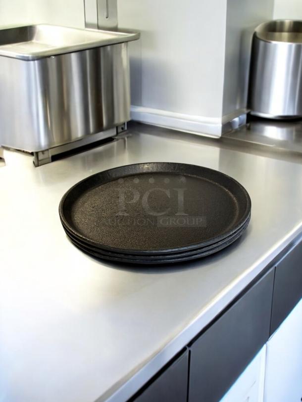 Set of 3 cast iron pizza pans in excellent condition, stacked on a kitchen counter. Fully tested, ready to use.