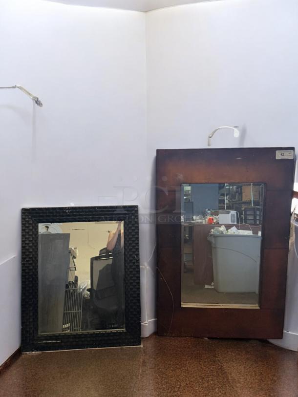 Set of 2 decorative wall mirrors, one with a textured black frame, the other with a wooden frame. Excellent condition.
