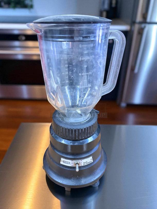 Waring BB150 Commercial Blender in good condition. Features 120V power, clear jar, and control switch with brand label.
